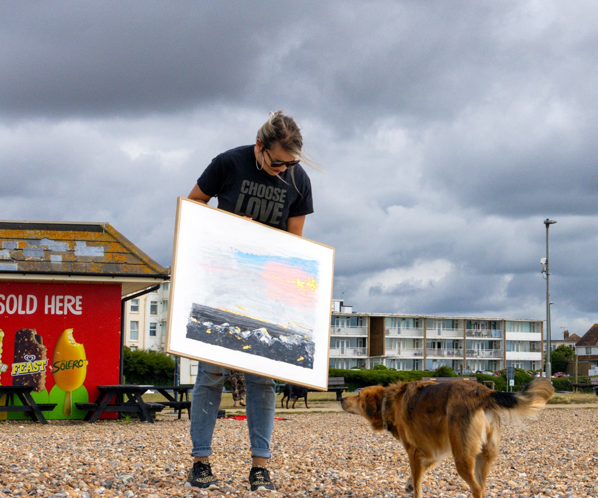 Jo Conlon on the beach carrying rain or shine with her dog missy running towards her